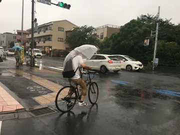 雨の日の交差点を自転車で走る人