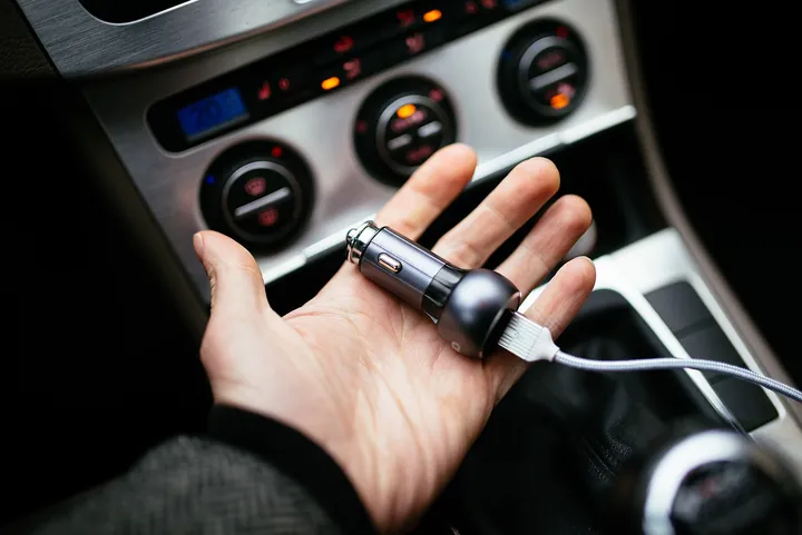 車のソケットにUSB充電器を差し込む手