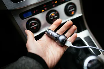 車のソケットにUSB充電器を差し込む手