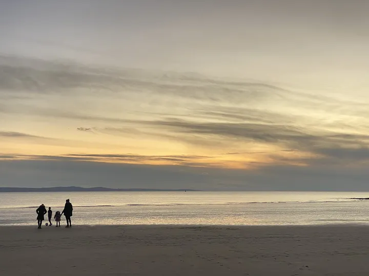 夕方の砂浜を歩く家族