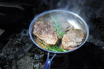 小型のガスバーナーで肉を焼く（屋外の調理）