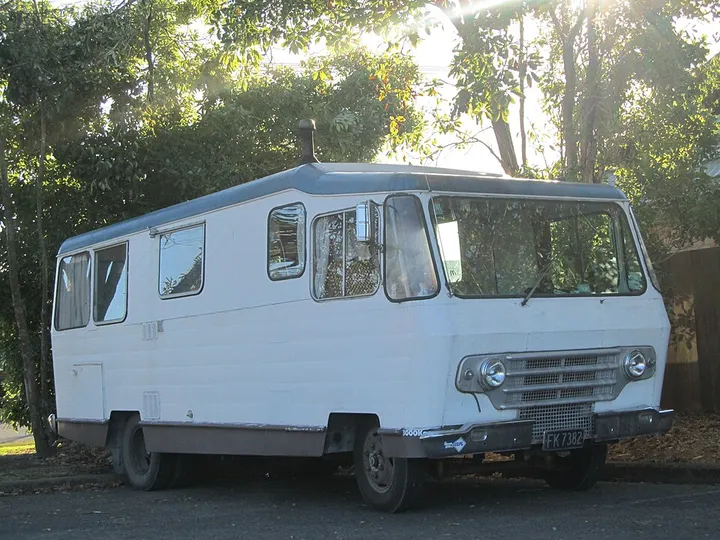 白い大型のキャンピングカー（バス型の古い車体）