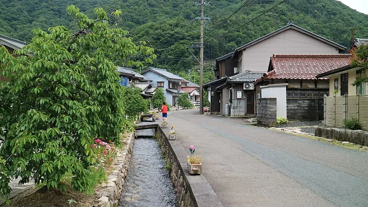 山あいの町並みと細い水路のある道